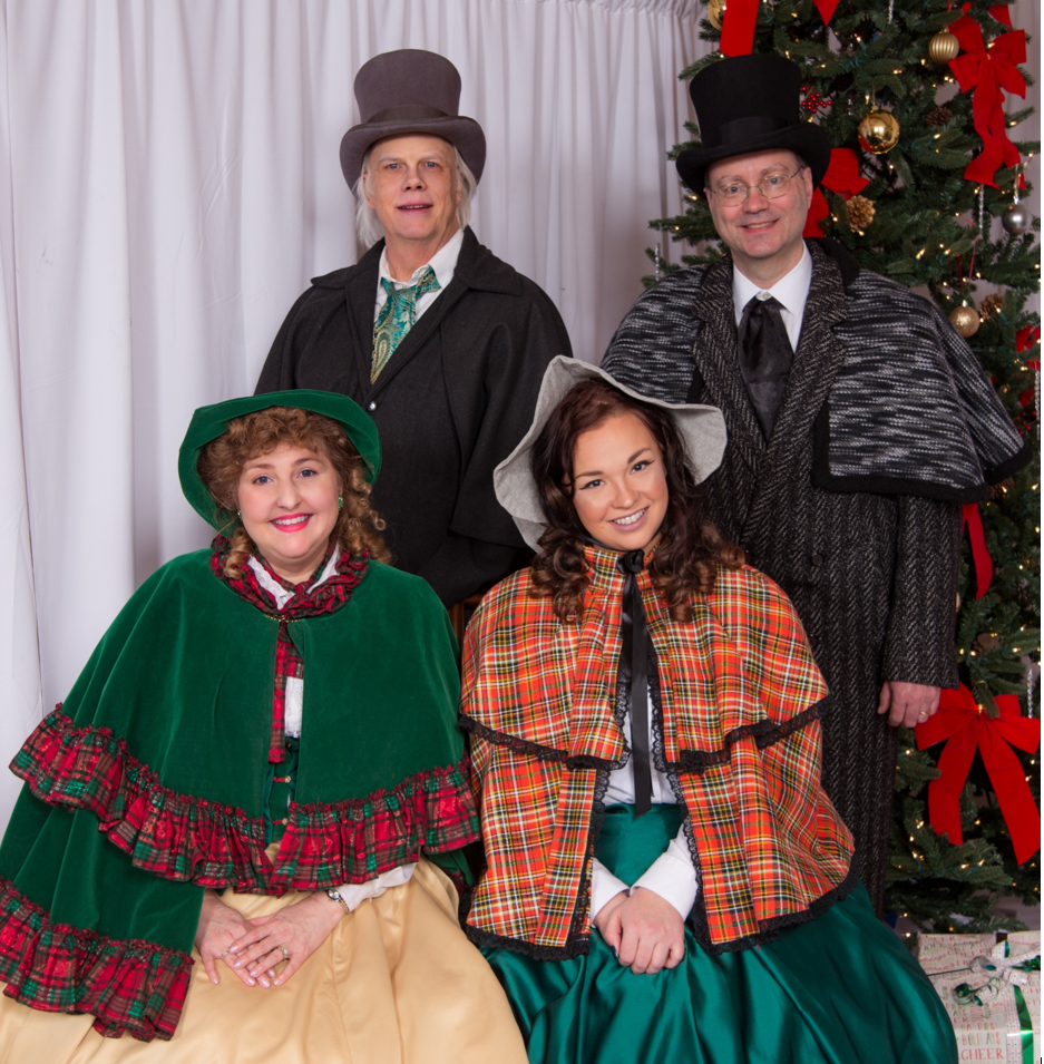 Two men and two women dressed in Victorian holiday attire