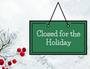 A green sign that says, "Closed for the Holiday," on a snowy background with a red berry bush.