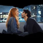 A man and woman talking on a couch with a city skyline in the background.