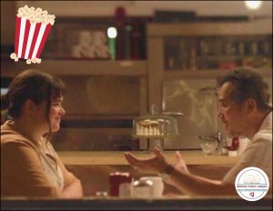 A photo of a young woman and an older man in a diner.