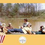 Three middle-aged couples on a boat on a pond.